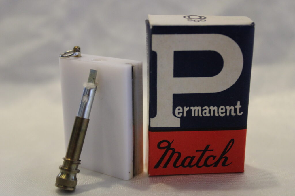 A permanent match alongside its white and blue packaging box labeled 'Permanent Match'.